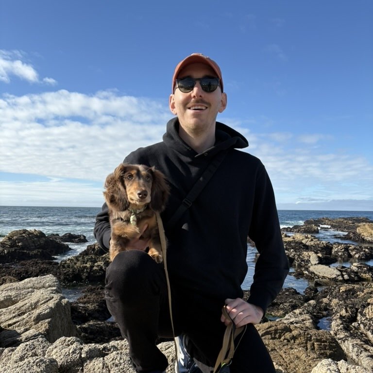 Alex King, Software Engineer, with his dachshund on the coast